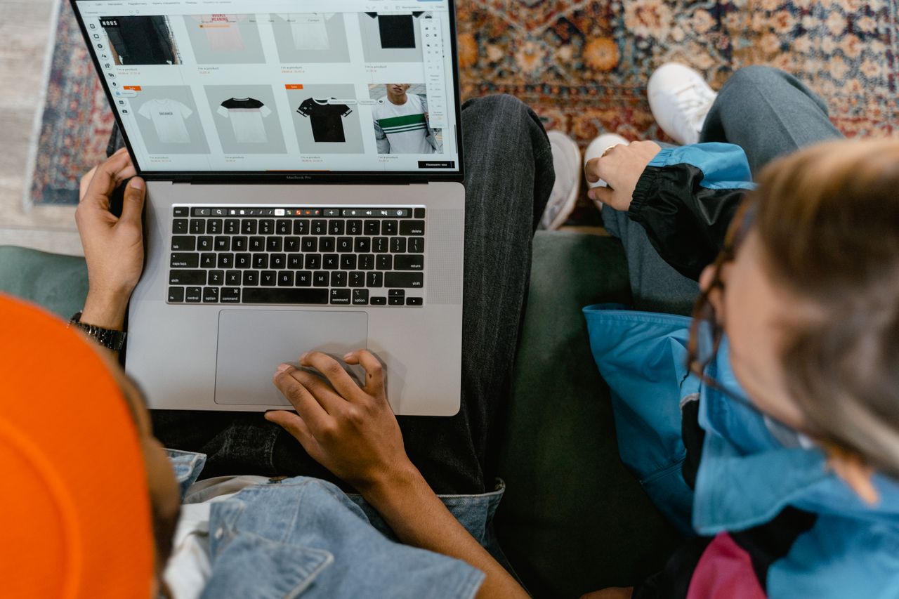 who-we-are Two people browsing online clothing store on a laptop from above.
