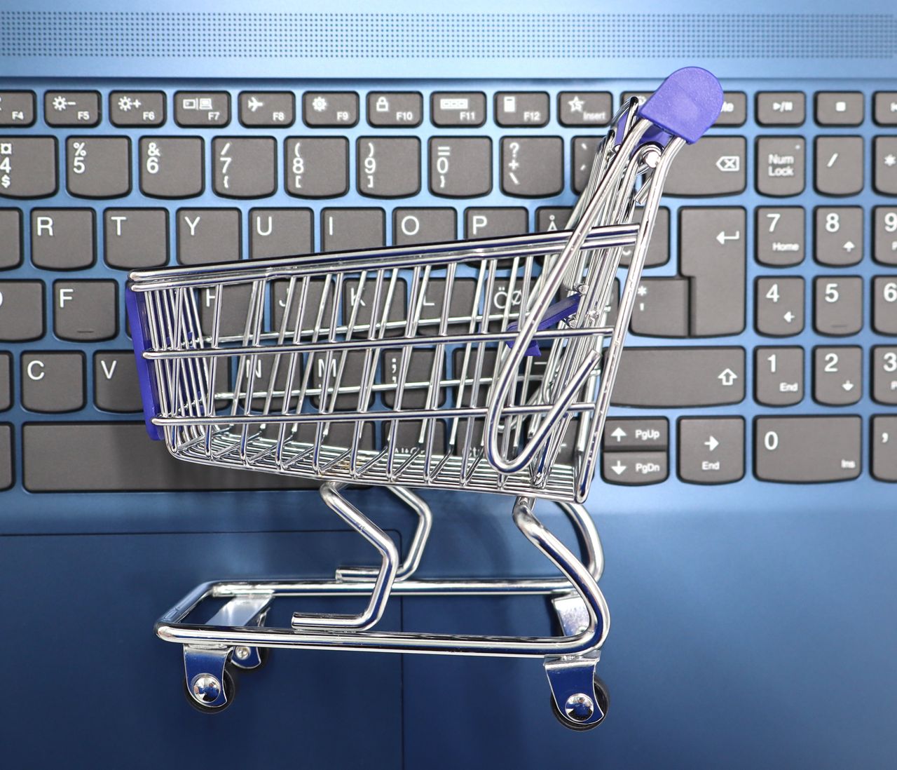 services-02 A miniature shopping cart placed on a laptop keyboard symbolizing online shopping and e-commerce.